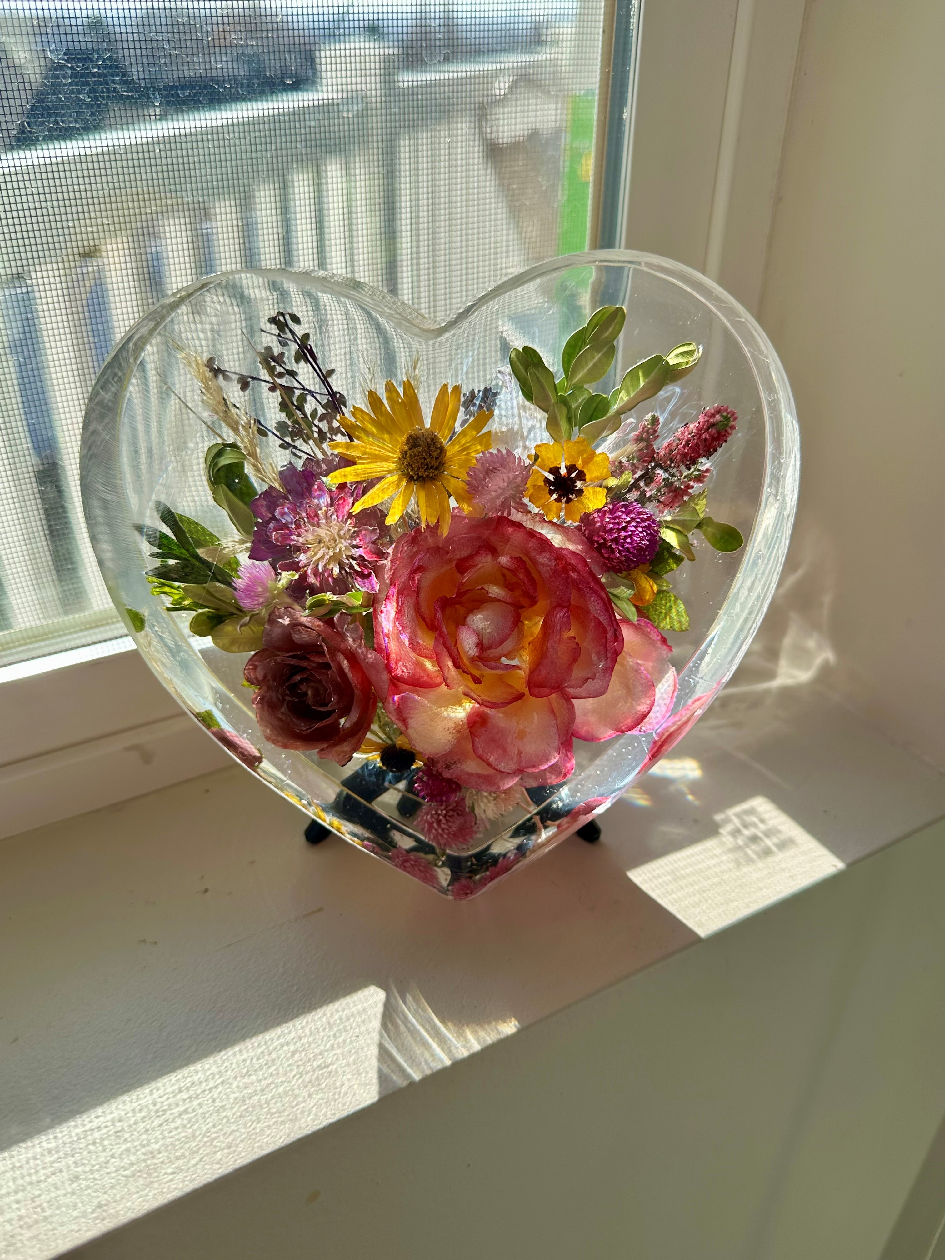 Resin-encased flowers in the shape of a heart as seen from the front, showing vibrant red and green colors