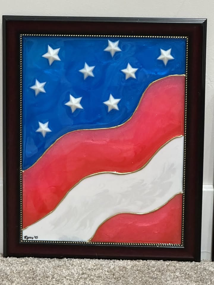 A stylized USA flag art piece in a frame with blue, red and white stripes and stars