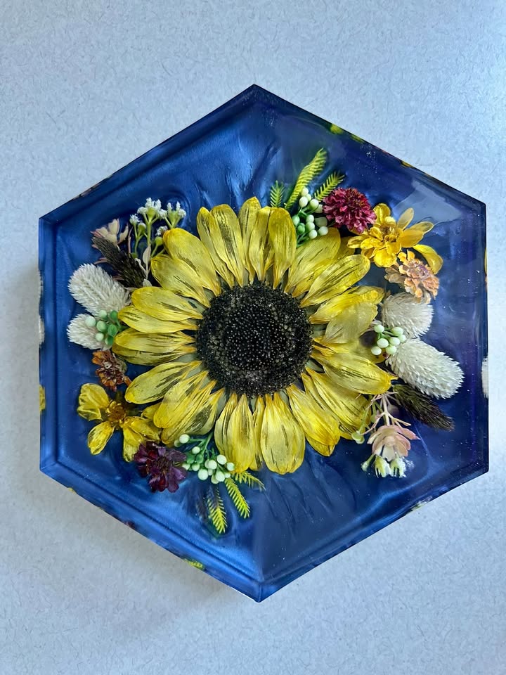 A deep resin pour containing a sunflower bloom with golden and green tones